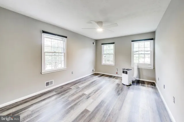 an empty room with wooden floor and windows