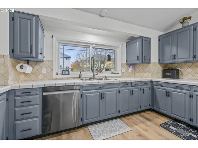 a kitchen with granite countertop a sink cabinets and stainless steel appliances