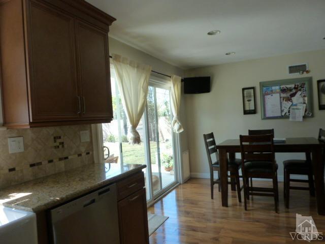 2239 Ralston Street Simi Valley, CA 93063 - Photo 9 of 29 a kitchen with stainless steel appliances granite countertop a table chairs in it and wooden floors