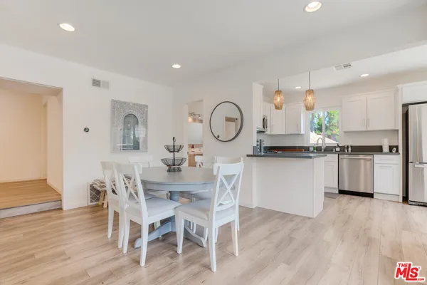 a kitchen with granite countertop a table chairs stove a sink and cabinets