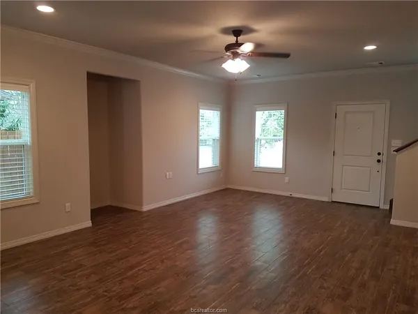 an empty room with wooden floor and windows