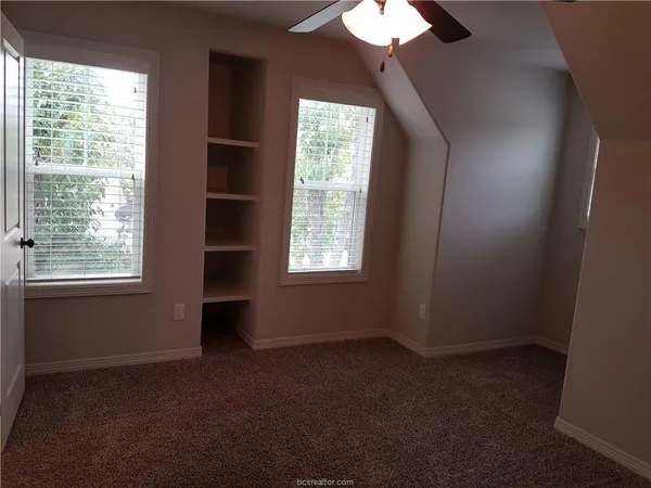 a view of an empty room with a bathroom and a window