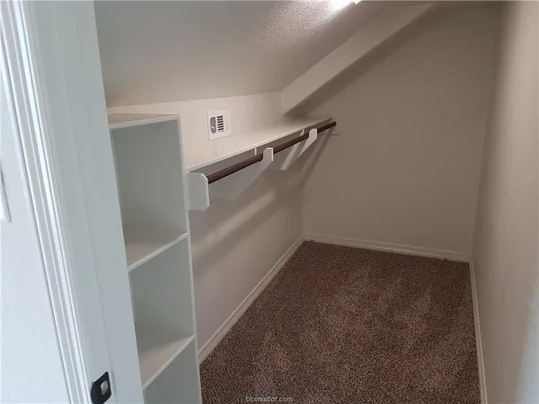 an empty room with closet and a chandelier fan