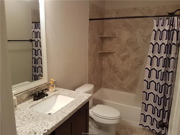 a bathroom with a granite countertop sink toilet and shower