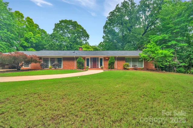 a view of a house with a yard and large tree