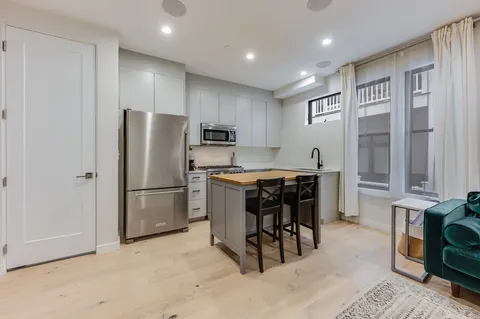 a kitchen with kitchen island a refrigerator and a stove top oven
