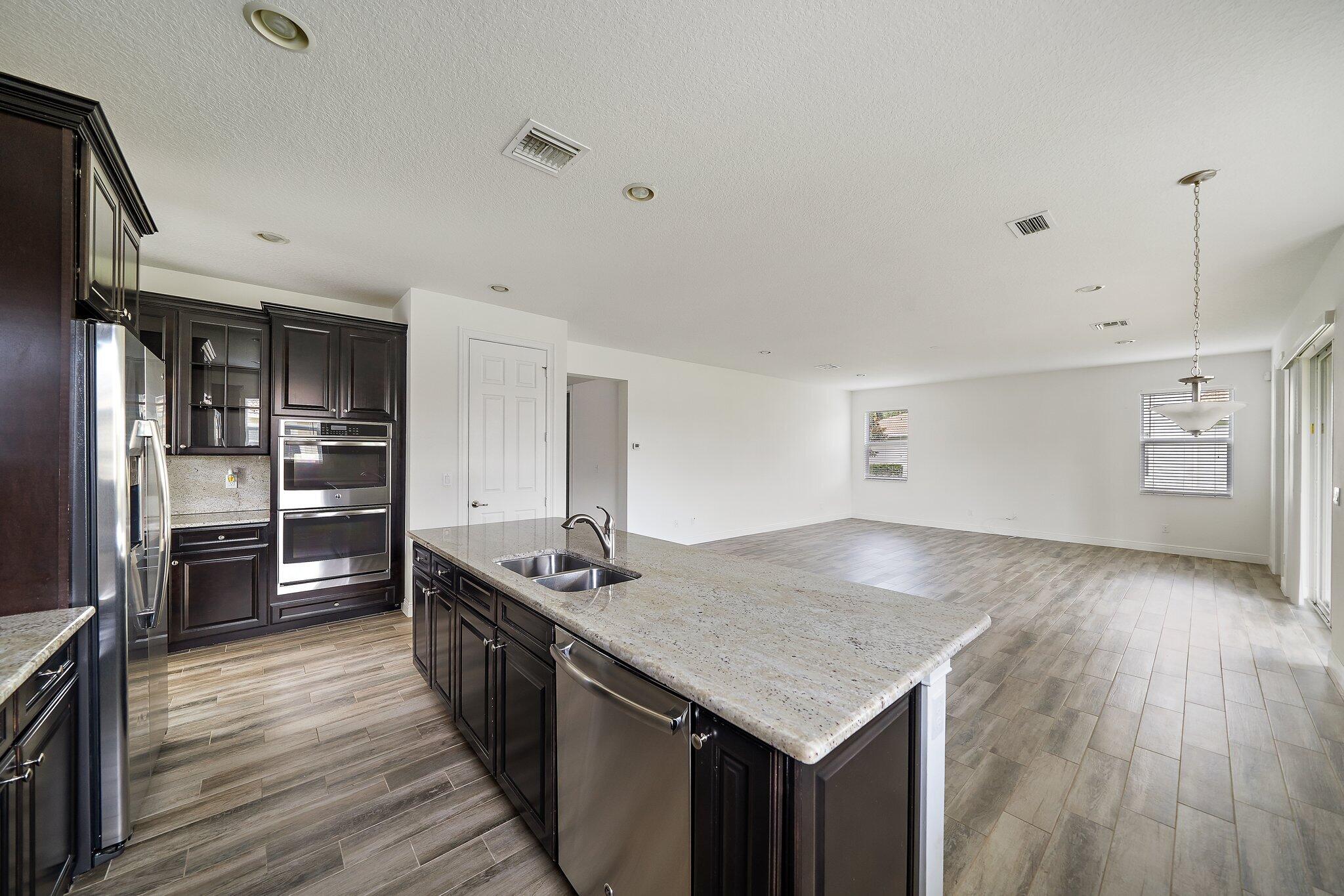 434 Rudder Cay Way Jupiter, FL 33458 - Photo 13 of 52 a kitchen with stainless steel appliances granite countertop a sink dishwasher stove and refrigerator with wooden floor