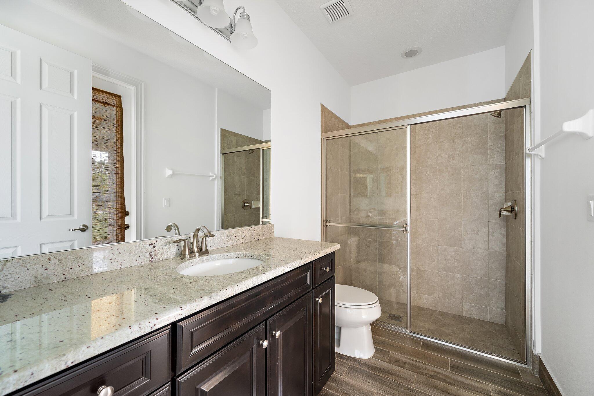 434 Rudder Cay Way Jupiter, FL 33458 - Photo 18 of 52 a bathroom with a granite countertop shower sink vanity mirror and toilet
