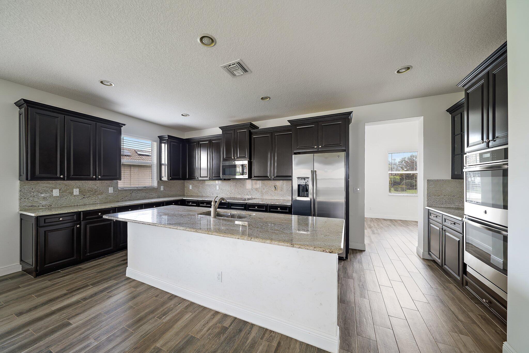 434 Rudder Cay Way Jupiter, FL 33458 - Photo 8 of 52 a large kitchen with stainless steel appliances granite countertop a stove refrigerator and a sink