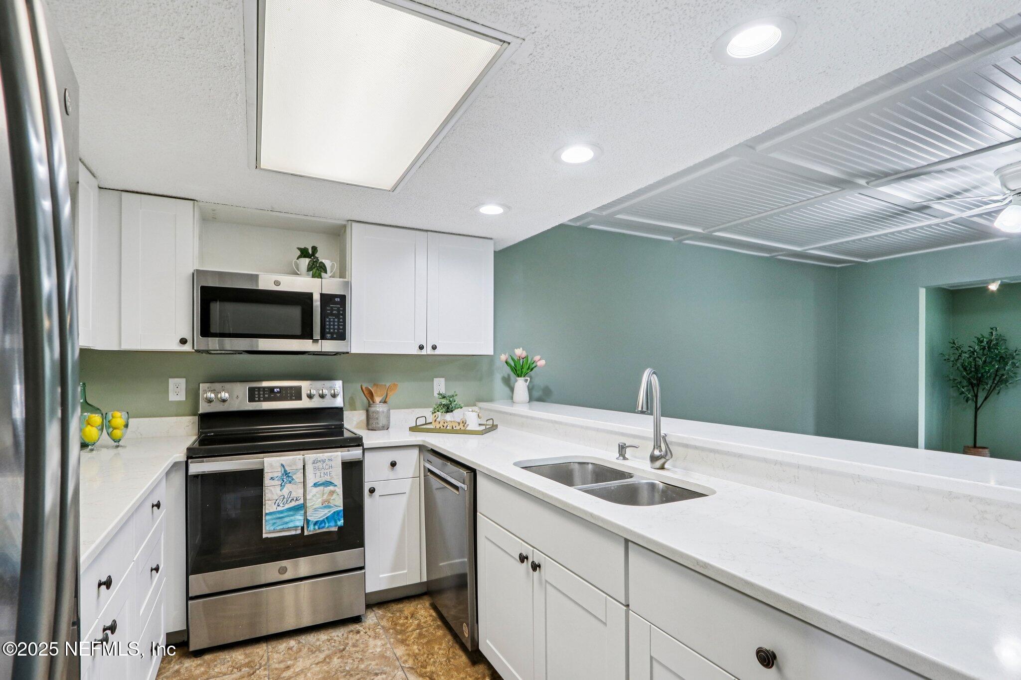 200 16th Street, Unit 103A St. Augustine Beach, FL 32080 - Photo 14 of 51 a kitchen with a sink appliances and cabinets
