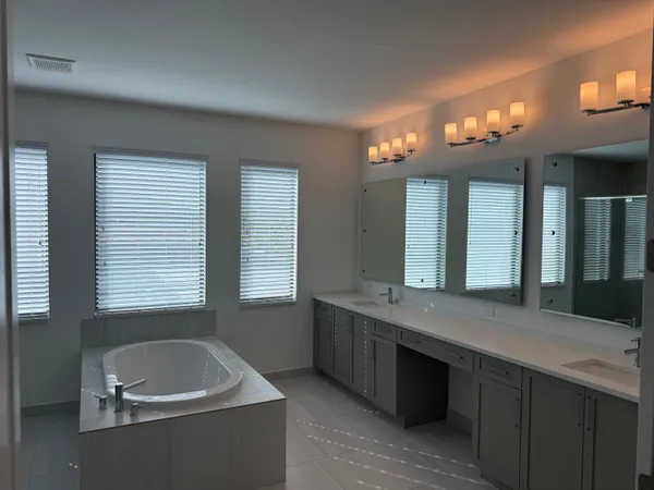 a bathroom with a granite countertop tub a double vanity sink and a large mirror