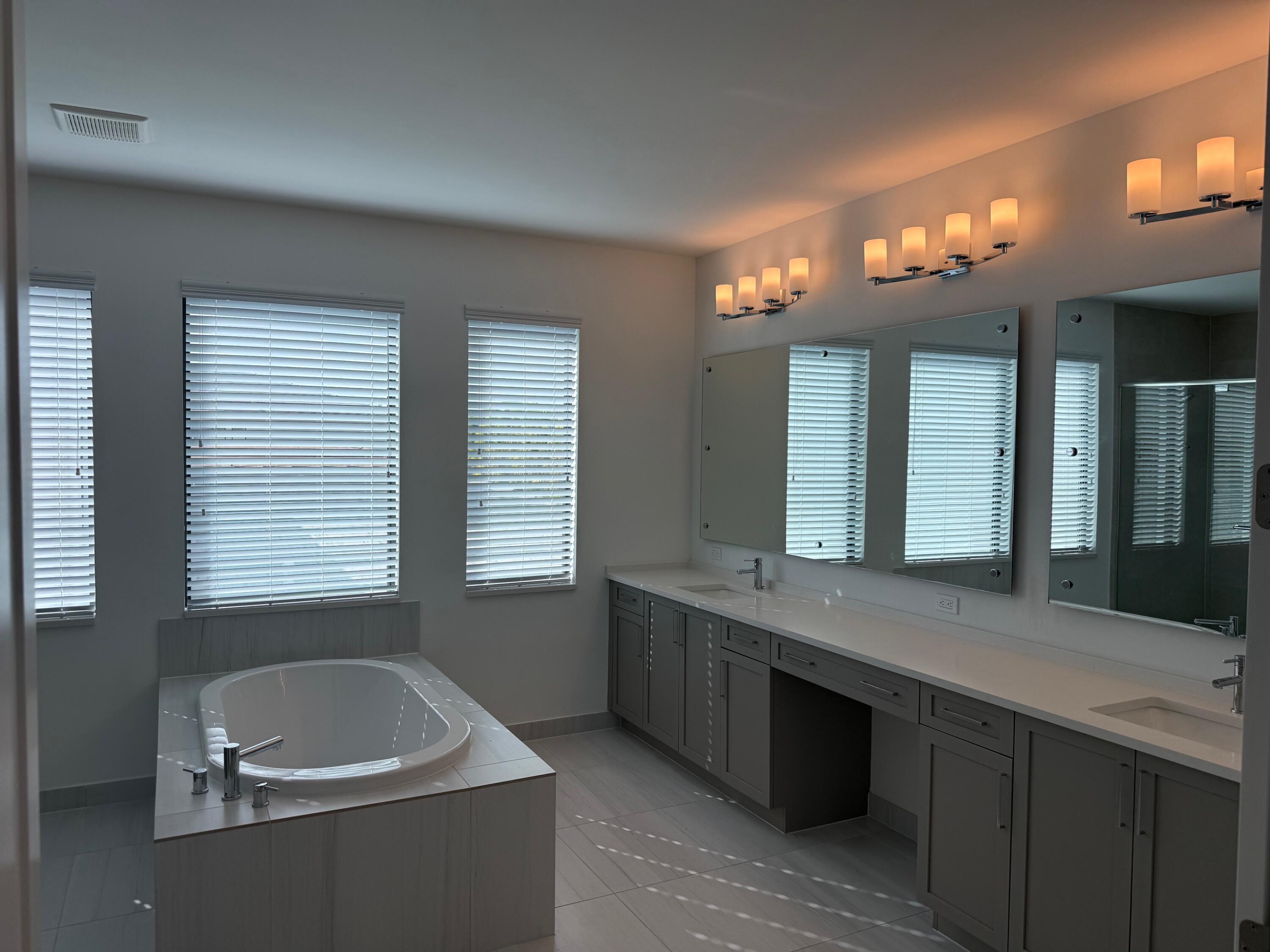 8055 White Wave Terrace Boca Raton, FL 33496 - Photo 10 of 20 a bathroom with a granite countertop tub a double vanity sink and a large mirror