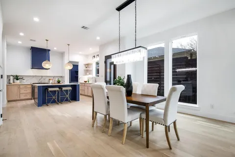 a kitchen with stainless steel appliances kitchen island granite countertop a dining table chairs and a refrigerator