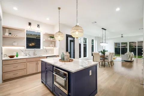 a kitchen with stainless steel appliances granite countertop a stove a sink a oven and a view of living room