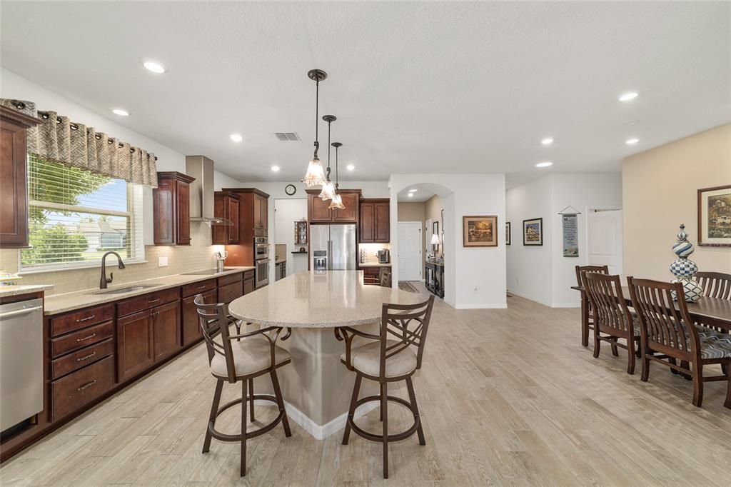 6479 Southwest 94th Circle Ocala, FL 34481 - Photo 19 of 82 a kitchen with stainless steel appliances kitchen island granite countertop a table chairs and wooden floor