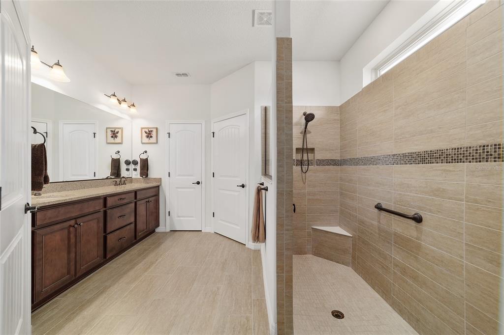 6479 Southwest 94th Circle Ocala, FL 34481 - Photo 38 of 82 a large bathroom with a granite countertop sink a mirror a bathtub and shower