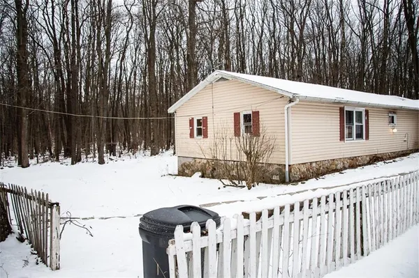 a backyard of white house with wooden fence
