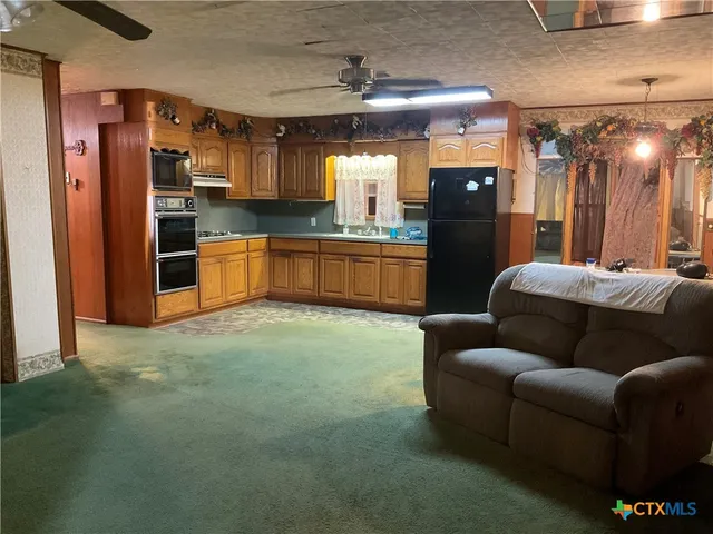 a living room with stainless steel appliances kitchen island granite countertop furniture and a refrigerator