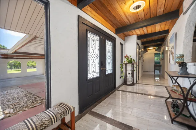 a spacious bedroom with a bed a table and potted plant with wooden floor