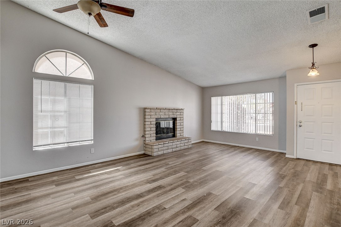 6209 Warm River Road Las Vegas, NV 89108 - Photo 8 of 39 A generous living area showcases vaulted ceilings, plank flooring, and a classic brick fireplace.