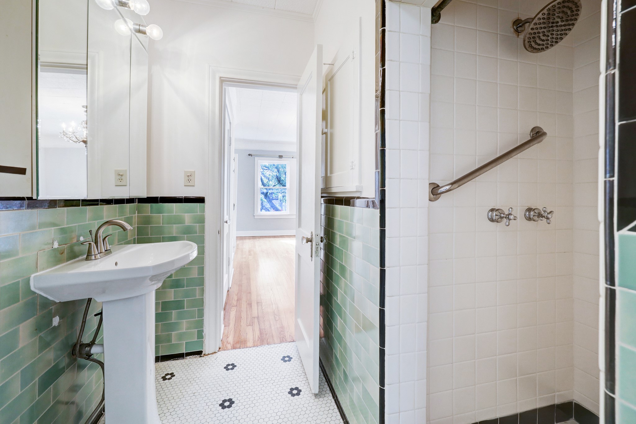 1950 Lexington Street Houston, TX 77098 - Photo 14 of 16 This primary bathroom showcases period-appropriate finishes, including a pedestal sink, decorative hex tile flooring, and subway tile walls. The space includes a walk-in shower in a classic Hollywood bath style and provides convenient access to the adjoining bonus/flex room.