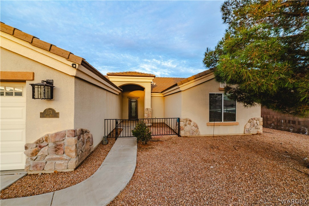 3374 Roma Road Kingman, AZ 86401 - Photo 2 of 64 View of front of home with a gate, stucco siding, a tiled roof, and stone siding