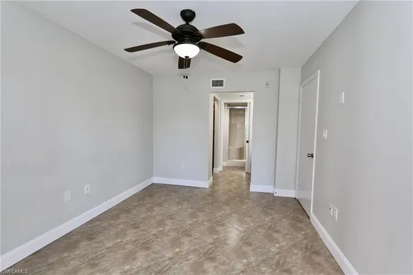 an empty room with windows and fan