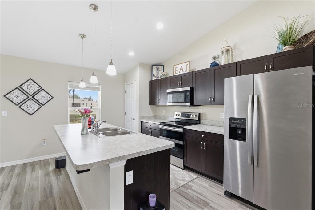 13880 Southwest 45th Terrace Ocala, FL 34473 - Photo 8 of 19 a kitchen with stainless steel appliances a sink a stove a refrigerator cabinets and a dining table