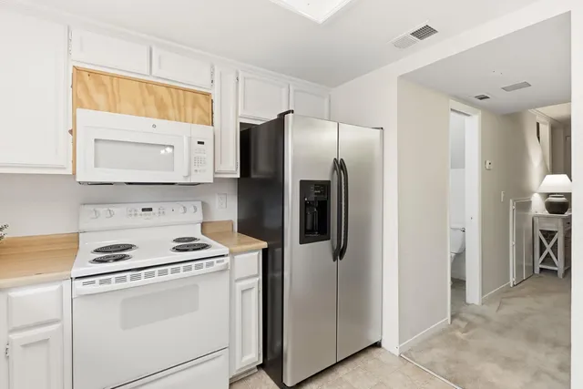 a kitchen with stainless steel appliances a refrigerator a stove and white cabinets