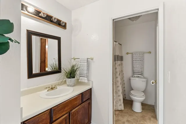 a bathroom with a granite countertop toilet a sink and a mirror