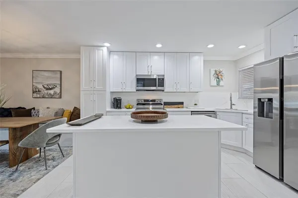 a kitchen with a refrigerator a stove a sink a dining table and chairs