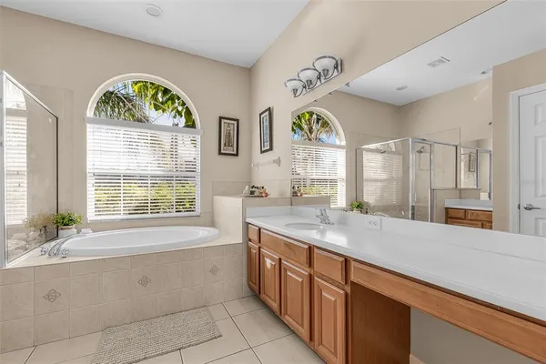 a spacious bathroom with a granite countertop tub a sink a window and a shower