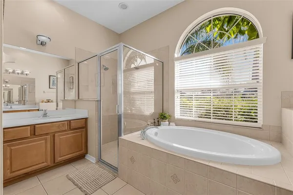 a spacious bathroom with a tub a sink a mirror and a window