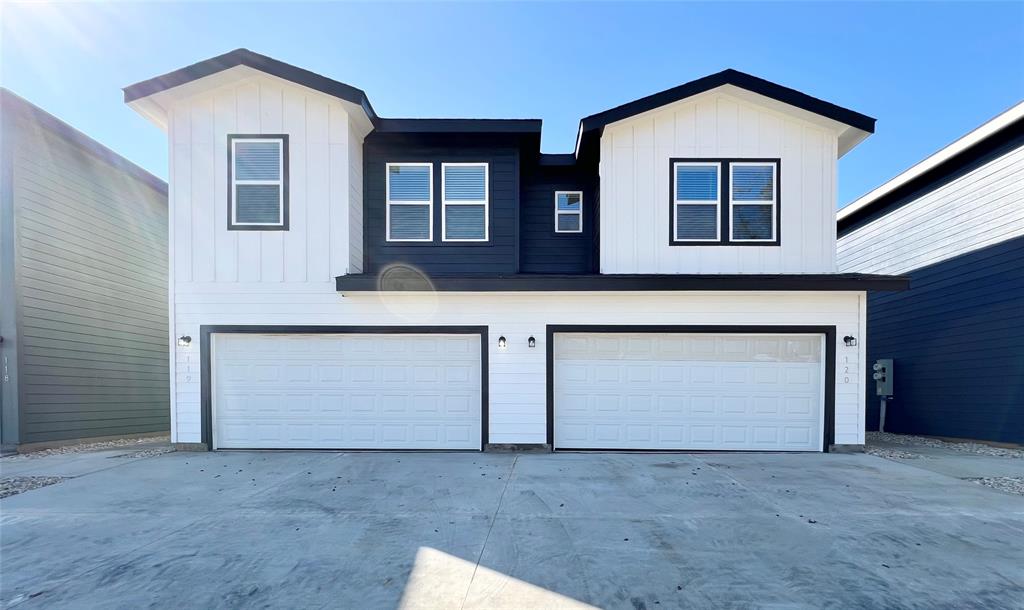 View of front of property with board and batten siding, an attached garage, and concrete driveway