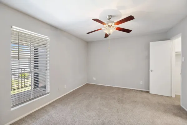 an empty room with windows and fan