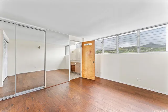 a view of an empty room with wooden floor and a window