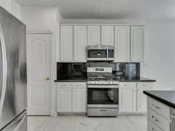 a kitchen with white cabinets and stainless steel appliances