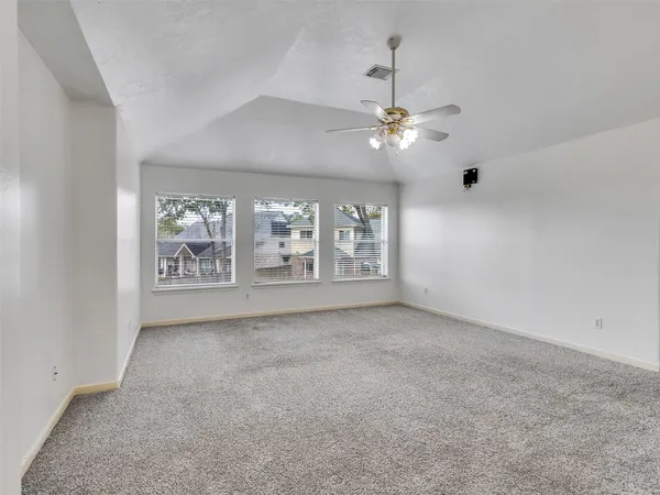 en empty room with windows and ceiling fan