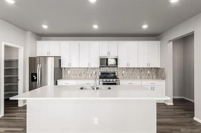a kitchen with stainless steel appliances a refrigerator sink and white cabinets