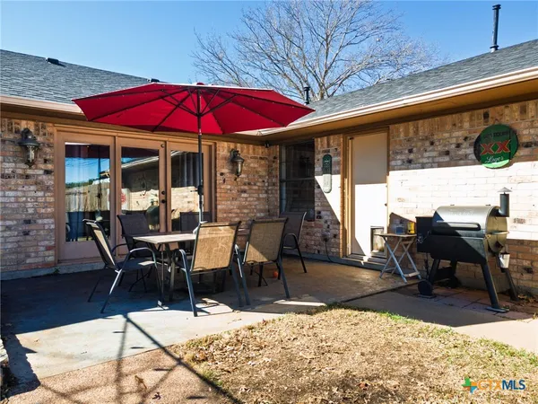 a view of a patio with table and chairs under an umbrella