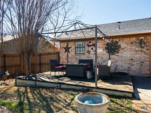 a view of a patio with table and chairs barbeque potted plants and large tree