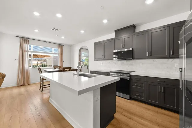 a kitchen with stainless steel appliances granite countertop a sink a stove a refrigerator and a microwave with wooden floor