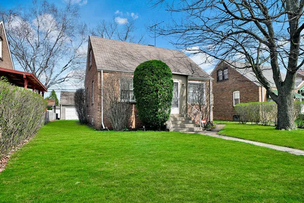 a brick house with a big yard and large trees