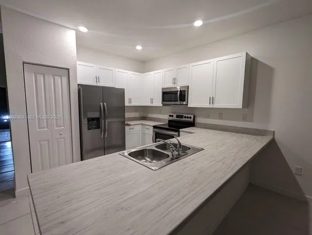 a kitchen with stainless steel appliances granite countertop a refrigerator stove top oven and sink