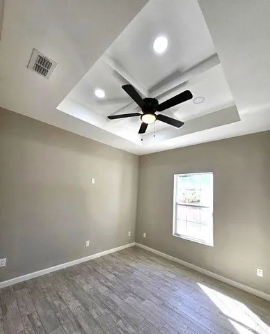 an empty room with wooden floor and windows