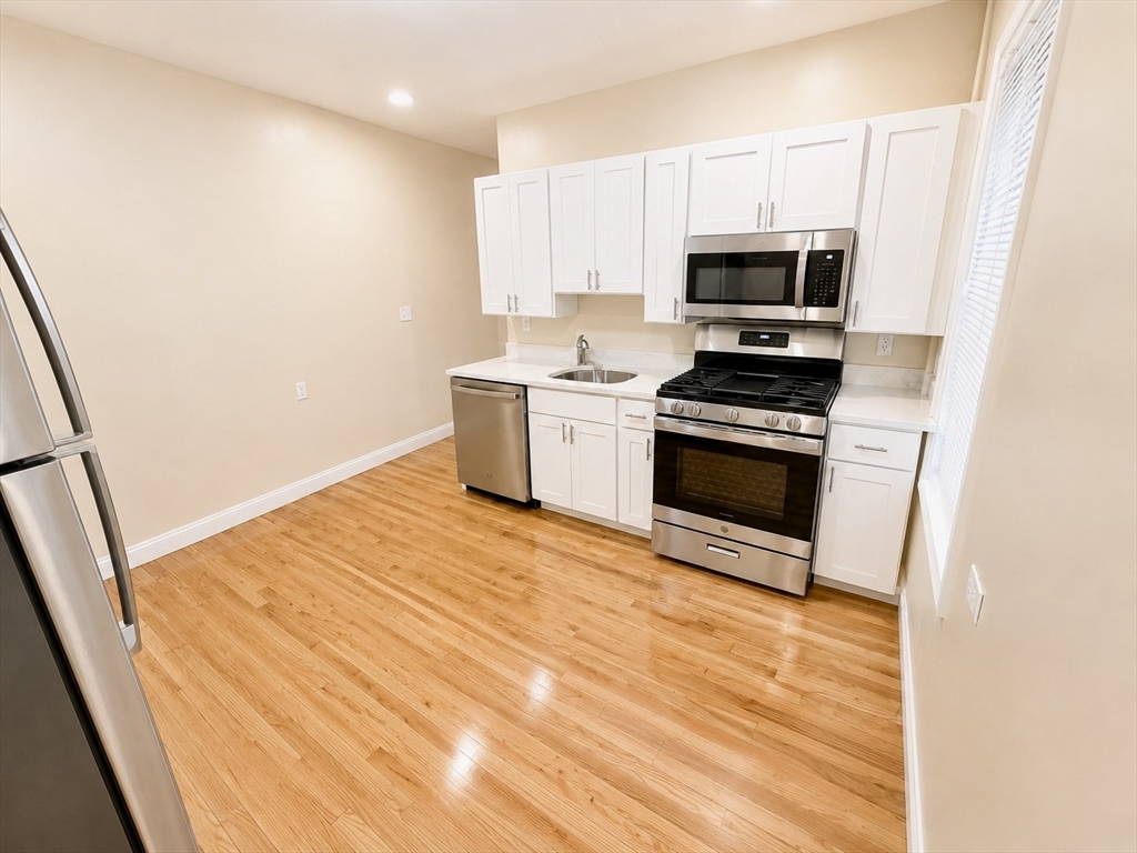 19 Dunlap Street, Unit 1 Boston, MA 02124 - Photo 9 of 9 a kitchen with stainless steel appliances a stove a microwave and a hard wood floor