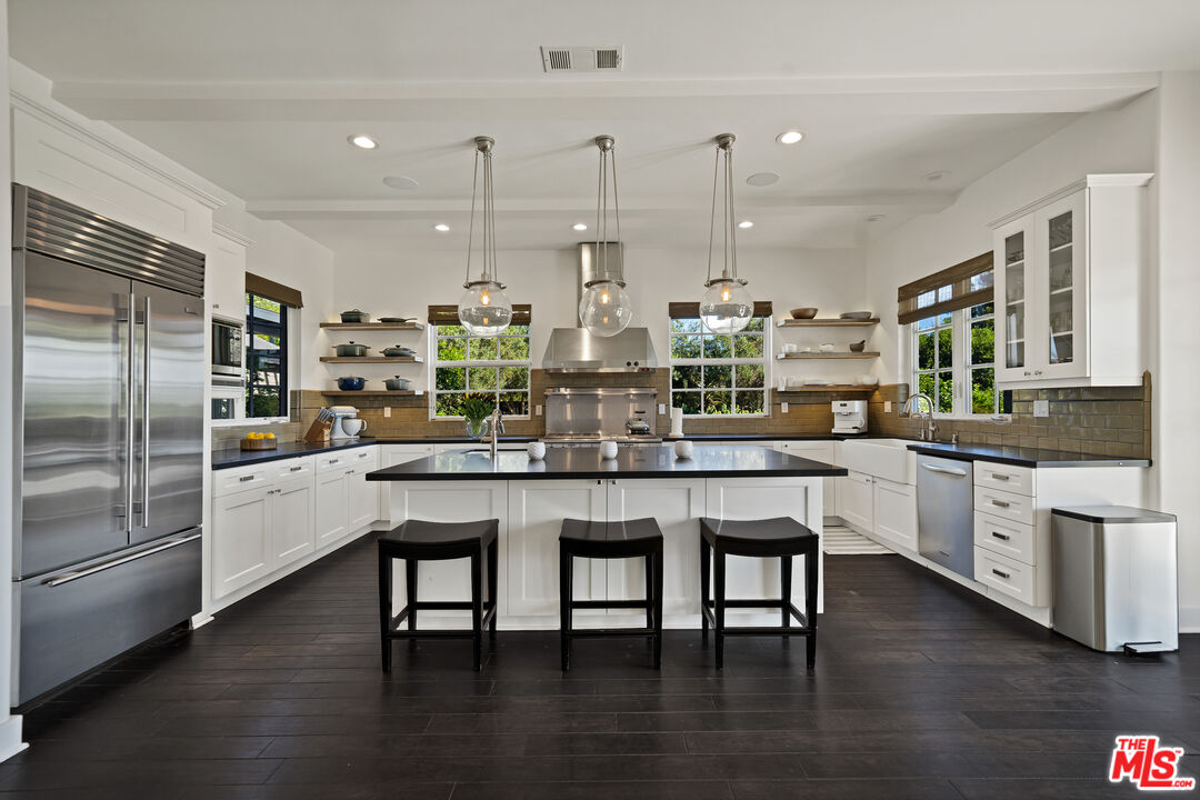 28850 Hampton Place Malibu, CA 90265 - Photo 12 of 58 a kitchen with stainless steel appliances granite countertop a kitchen island a stove a refrigerator a kitchen island a table and chairs