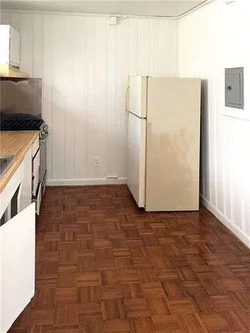 a view of a kitchen with fridge and wooden floor