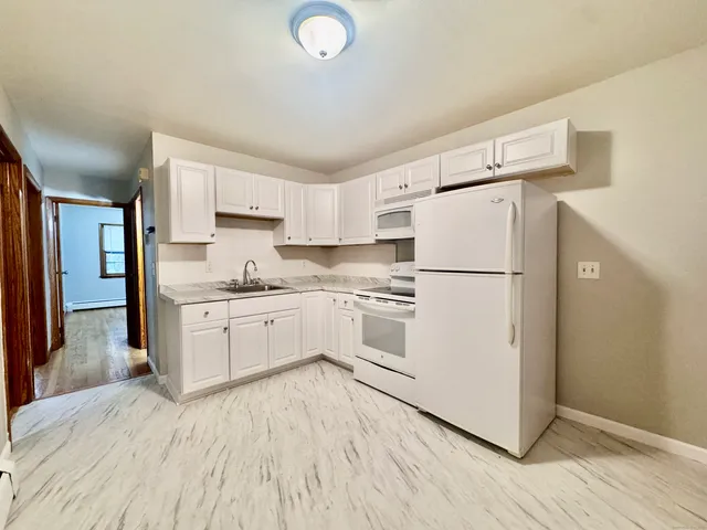 a kitchen with white cabinets and white appliances