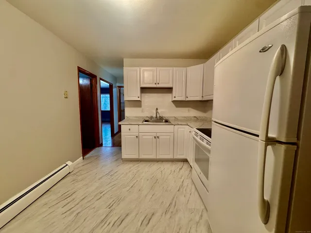 a kitchen with a refrigerator a stove top oven and white cabinets